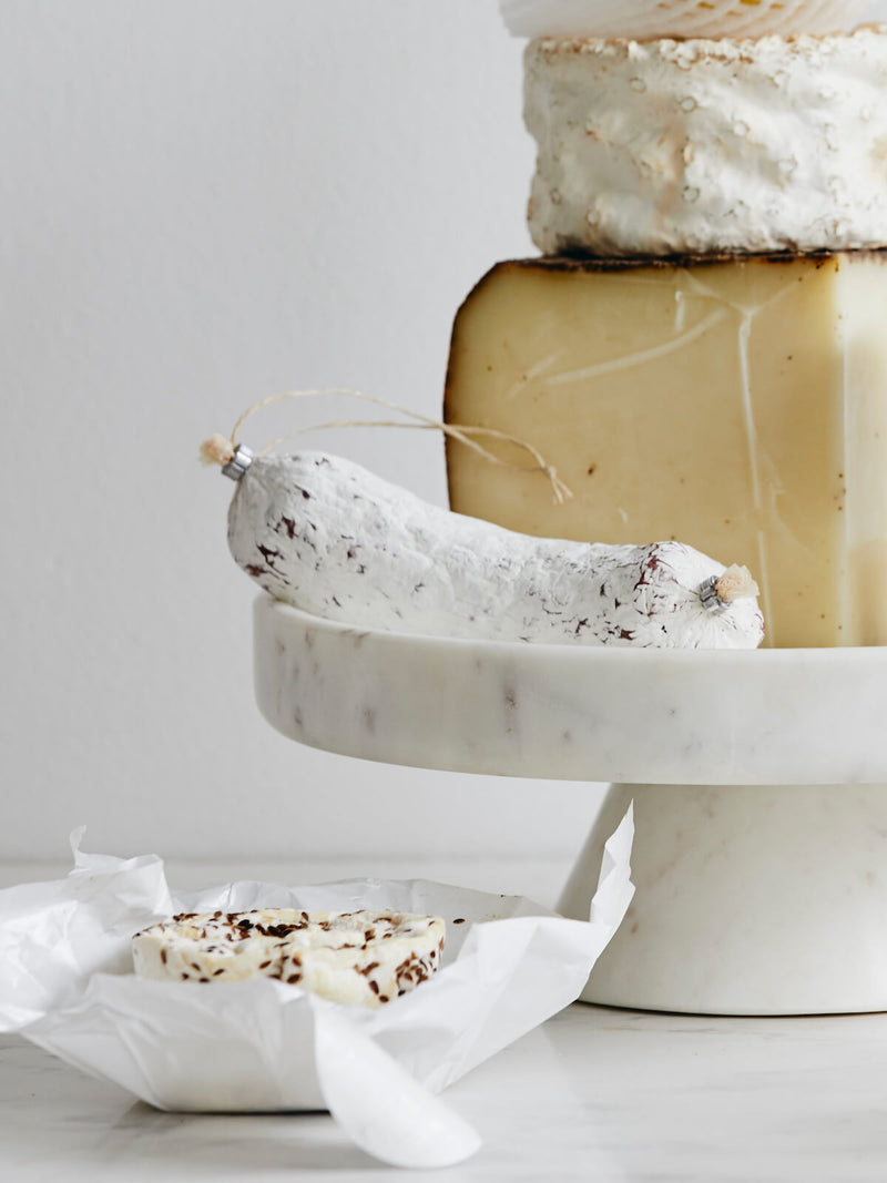 Stack of cheeses on a marble stand with a white background