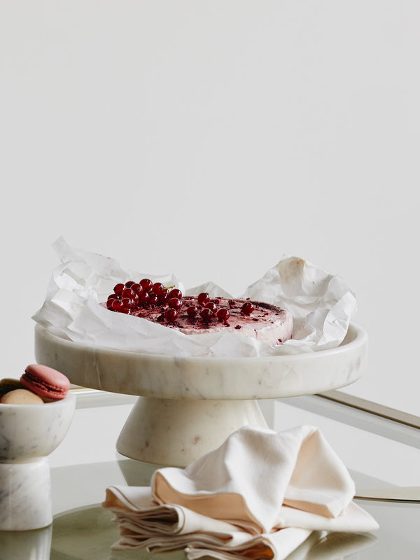Marble cake stand with a dessert and red berries on a light background