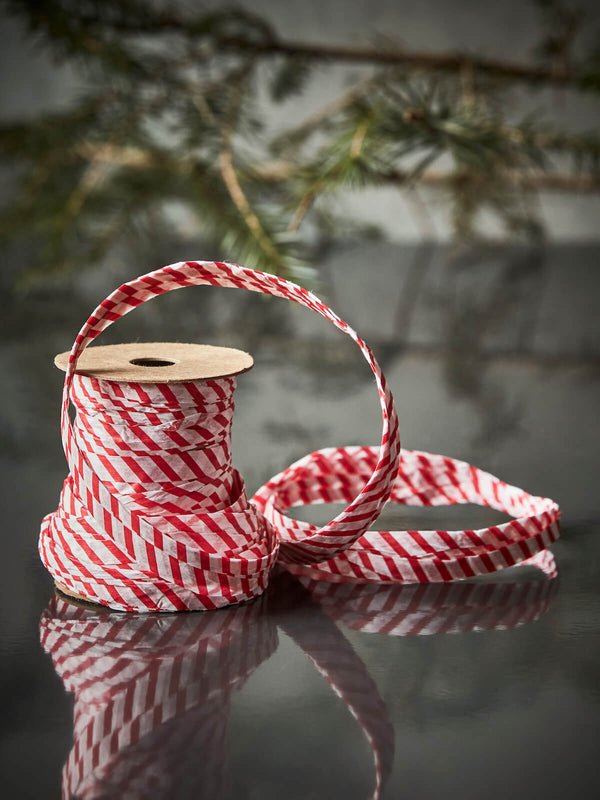 Bobbin of paper ribbon in white red Christmas theme, moody setting.