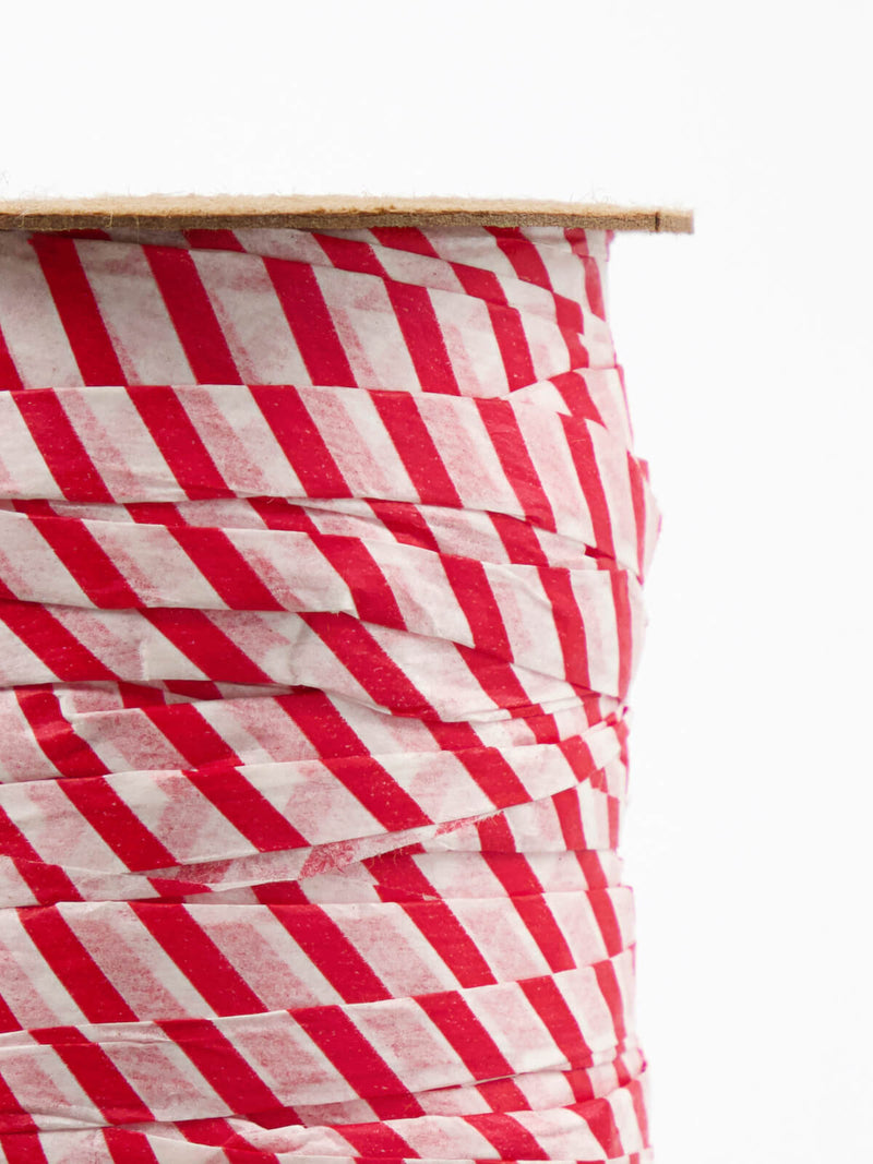 Closeup of Bobbin of paper ribbon in white red, white background.