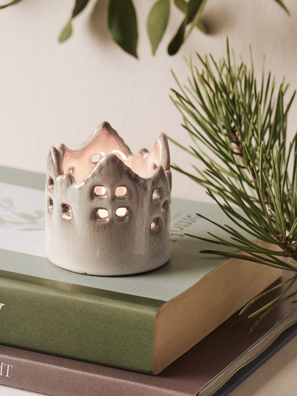 White ceramic house candle tealight holder by THATCH Living on a book with greenery in the background