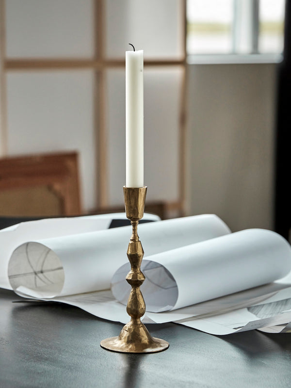 Gold rustic candlestick with character on a table.
