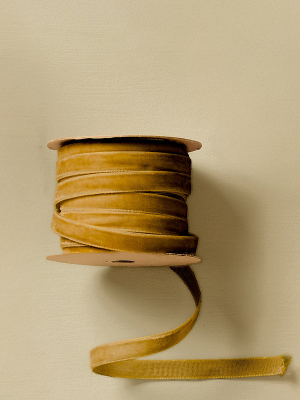 Spool of gold yellow clay ribbon by THATCH Living on a beige background