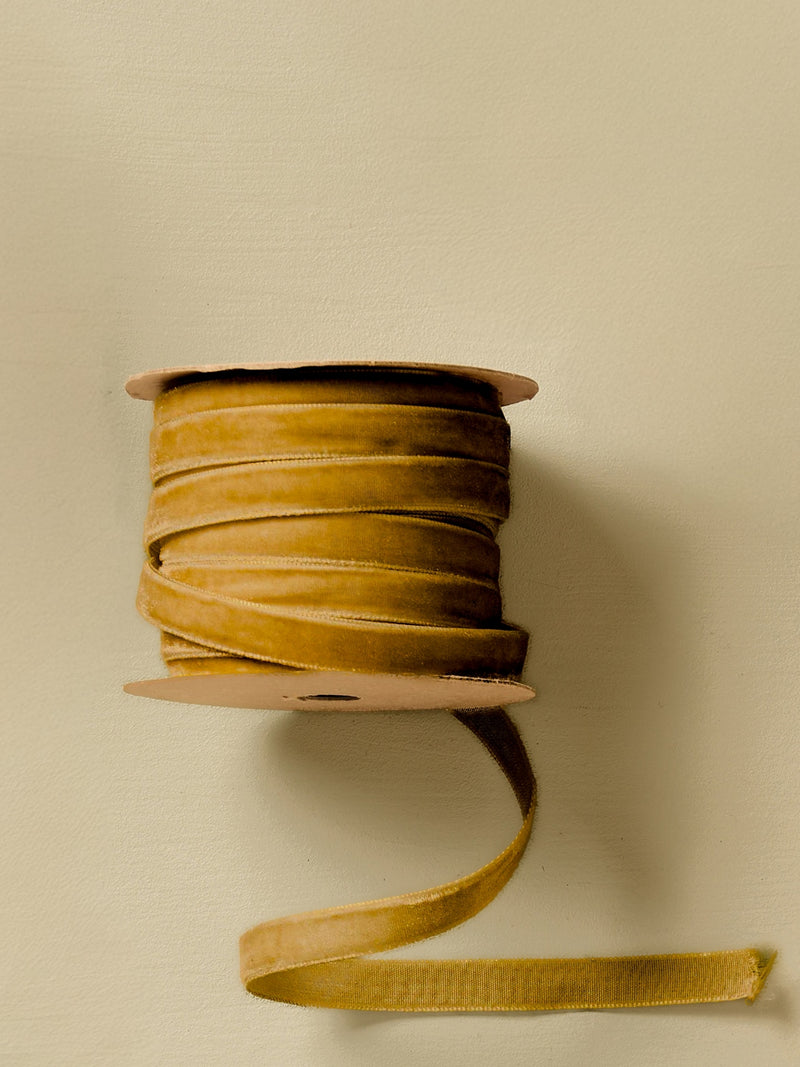 Spool of gold yellow clay ribbon by THATCH Living on a beige background