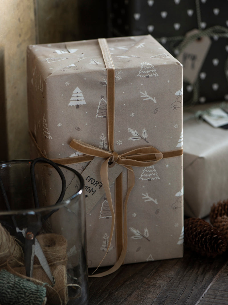 Gift box wrapped in patterned paper with a golden bow by THATCH Living, placed on a surface.