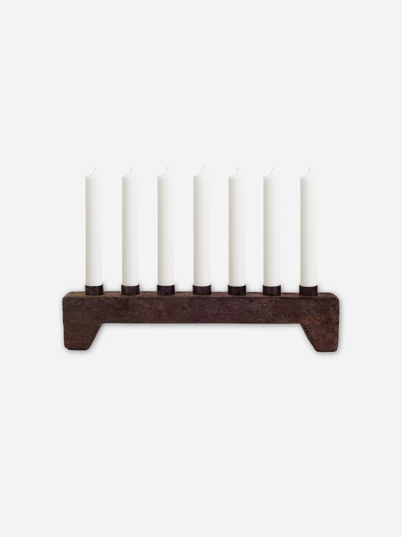 Wooden rustic candle holder from THATCH Living with seven white candles on a white background