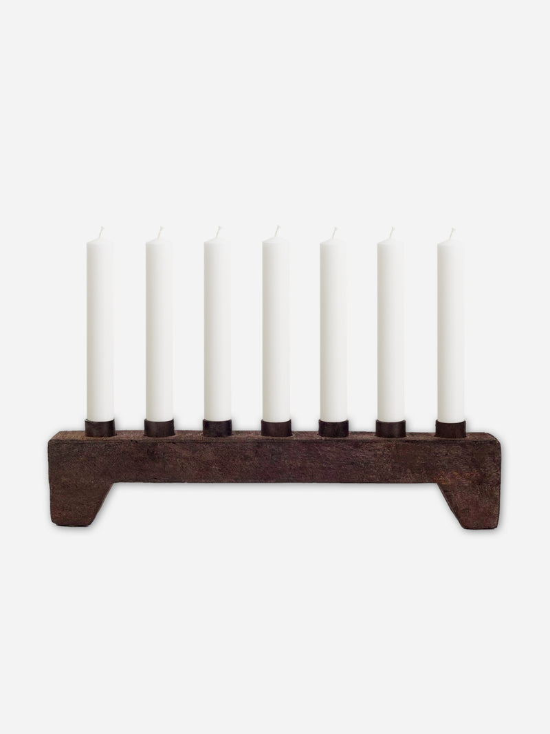 Wooden rustic candle holder from THATCH Living with seven white candles on a white background