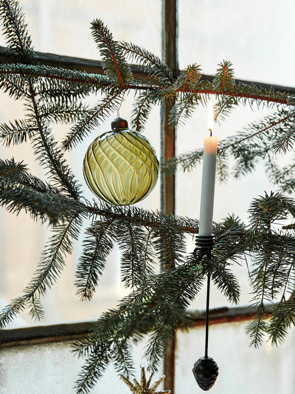 Green Christmas bauble made from glass on Christmas tree with candles.