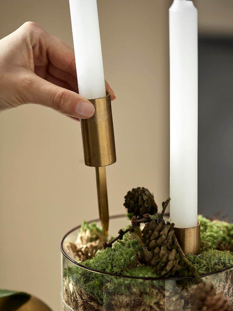 Hand applying gold candle spike into floral arrangement.