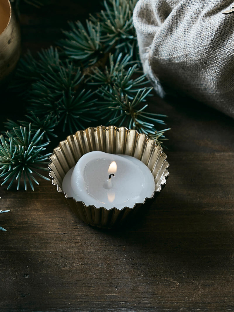 Gold decorative tealight holder in a festive setting, rustic table and greenery.