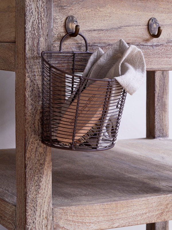 Wire basket by THATCH Living with a towel hanging on a wooden surface