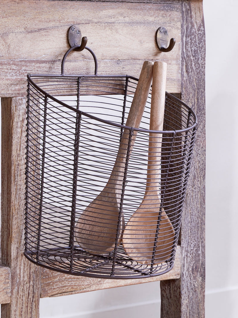 Wire basket by THATCH Living with wooden spoons hanging on a wooden rustic kitchen island.