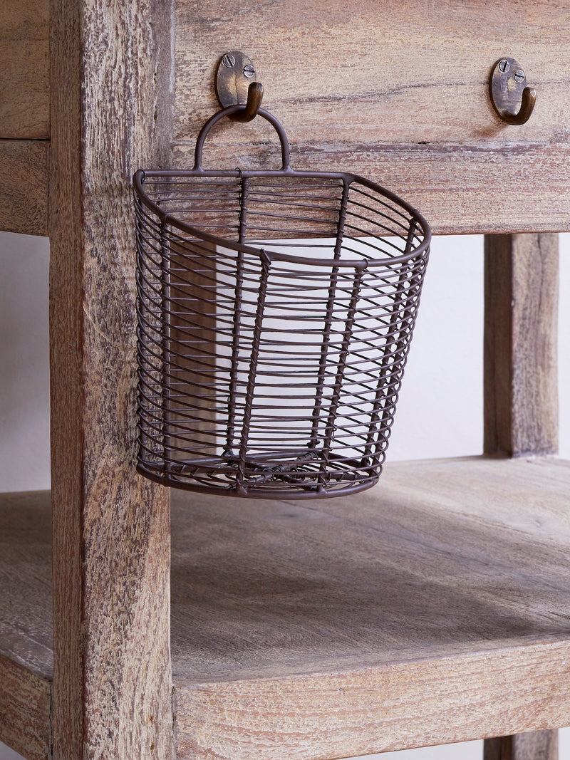 Wire basket by THATCH Living hanging on a wooden rustic shelf with a rustic background