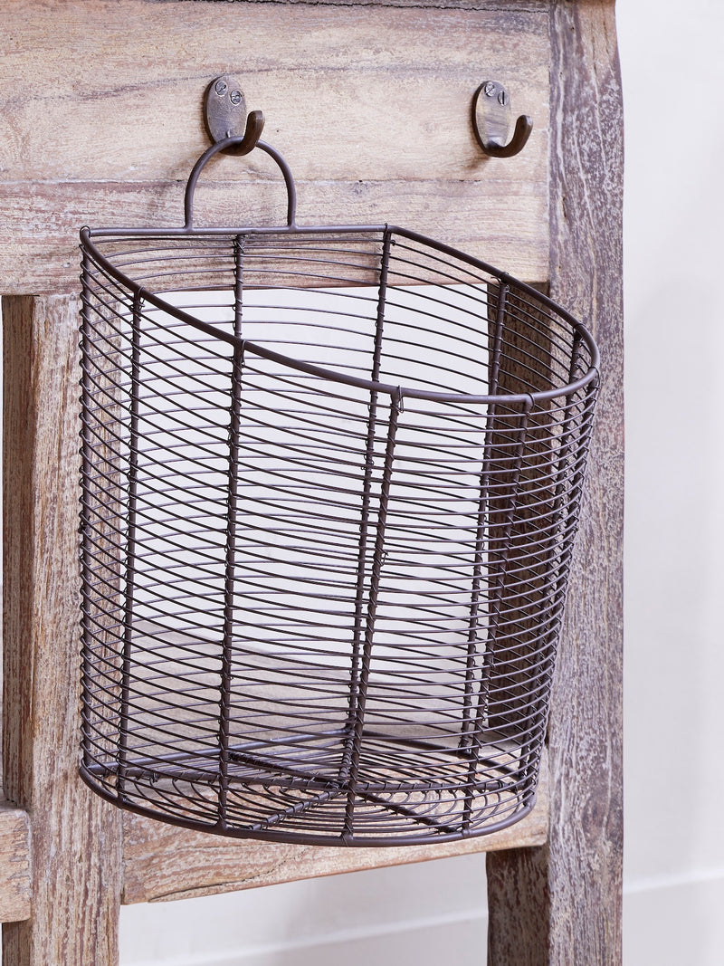 Wire basket by THATCH Living hanging on a rustic wooden surface with hooks.