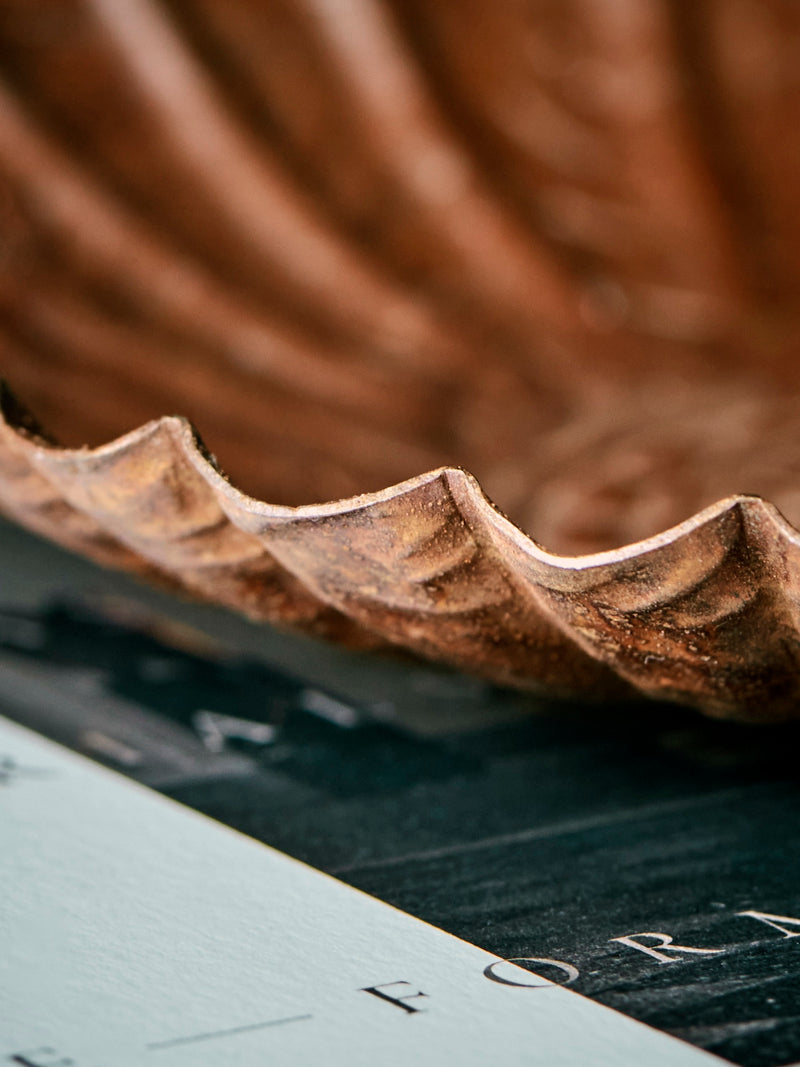 HDFofo brown decorative tray metal plate with scalloped edges on top of books on a rustic table and setting.