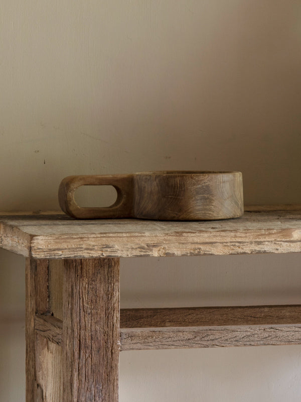 Wooden bowls on a rustic wooden table against a plain wall.