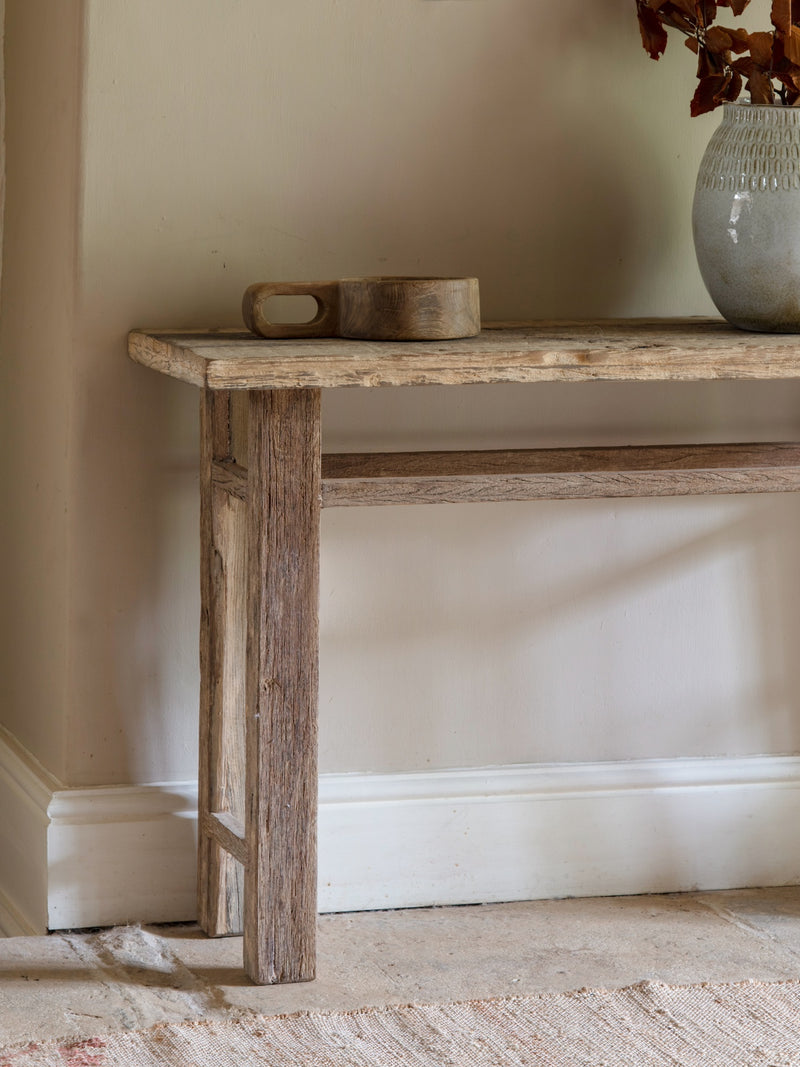 Wooden console table with a vase and bowl against a beige wall natural decor.