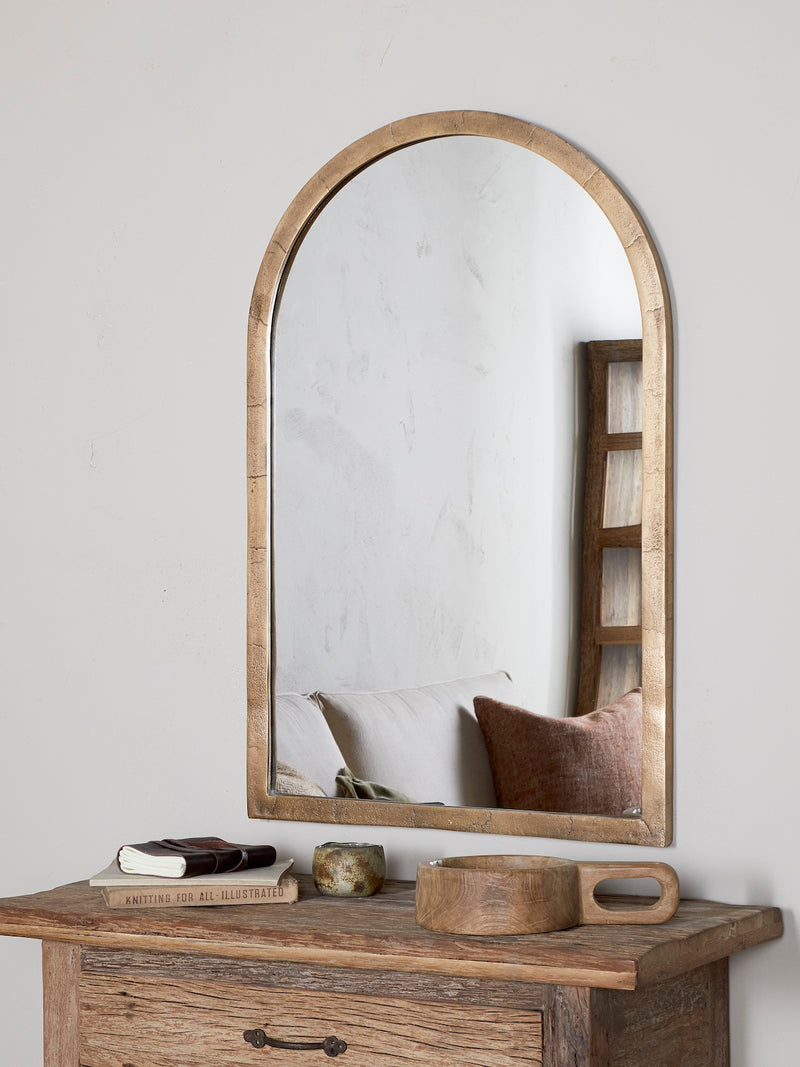 Wooden mirror with metal rustic frame on a wooden console table against a white wall with rustic bowl and natural decor.