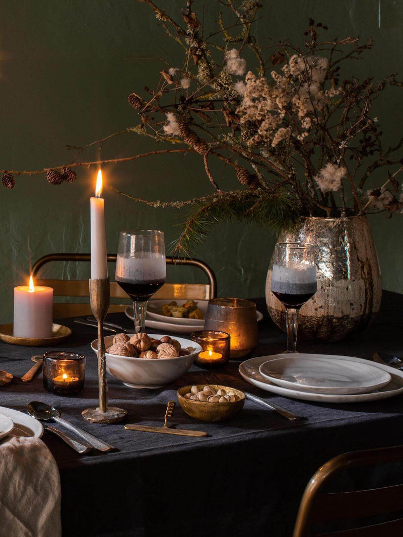 Christmas tablescape with candle light, golden accessories, wine decanter and floral arrangement
