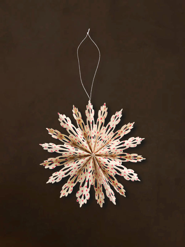 A recycled paper decorative snowflake ornaments by THATCH Living on a dark background