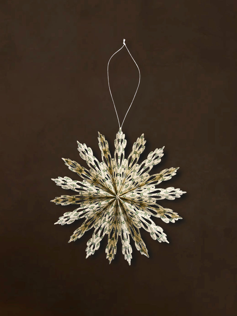 A recycled paper decorative snowflake ornaments by THATCH Living on a dark background