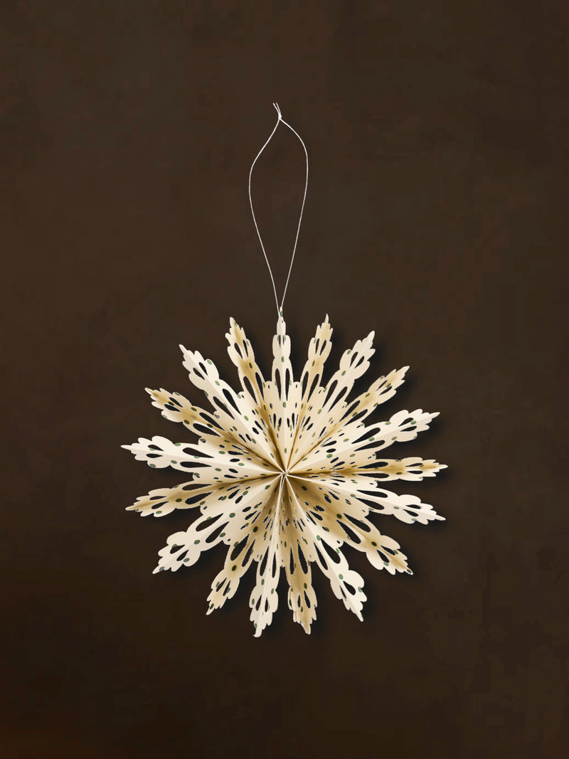 A recycled paper decorative snowflake ornaments by THATCH Living on a dark background