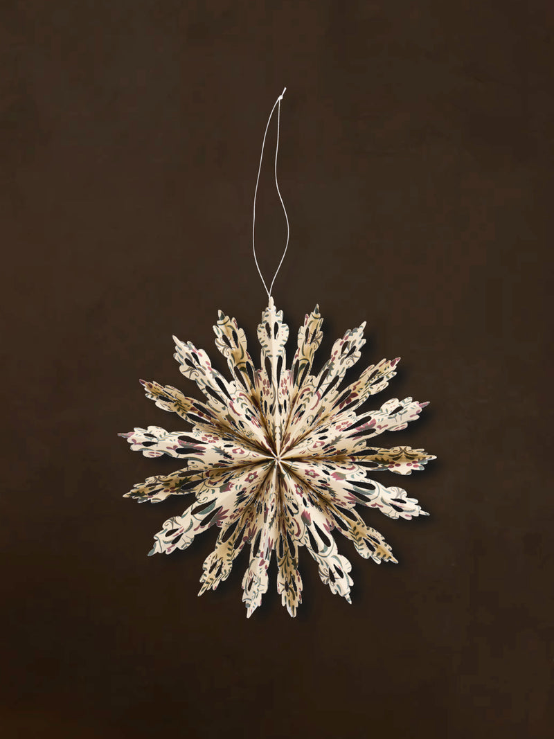 A recycled paper decorative snowflake ornaments by THATCH Living on a dark background