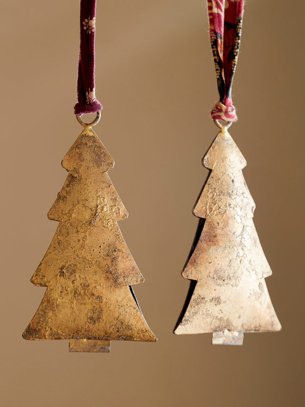 Two rustic tree-shaped ornaments by THATCH Living on ribbons against a beige background