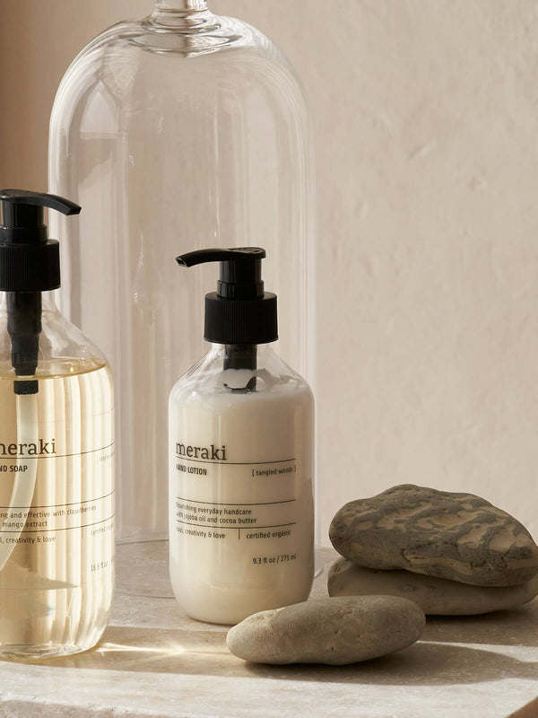 A bottle of Meraki Silky Mist hand lotion and hand wash on marble worktop.