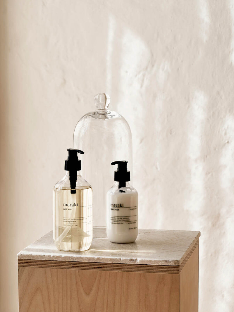 A set of Meraki hand lotion and hand soap handwash on top of marble worktop in a calm airy room.