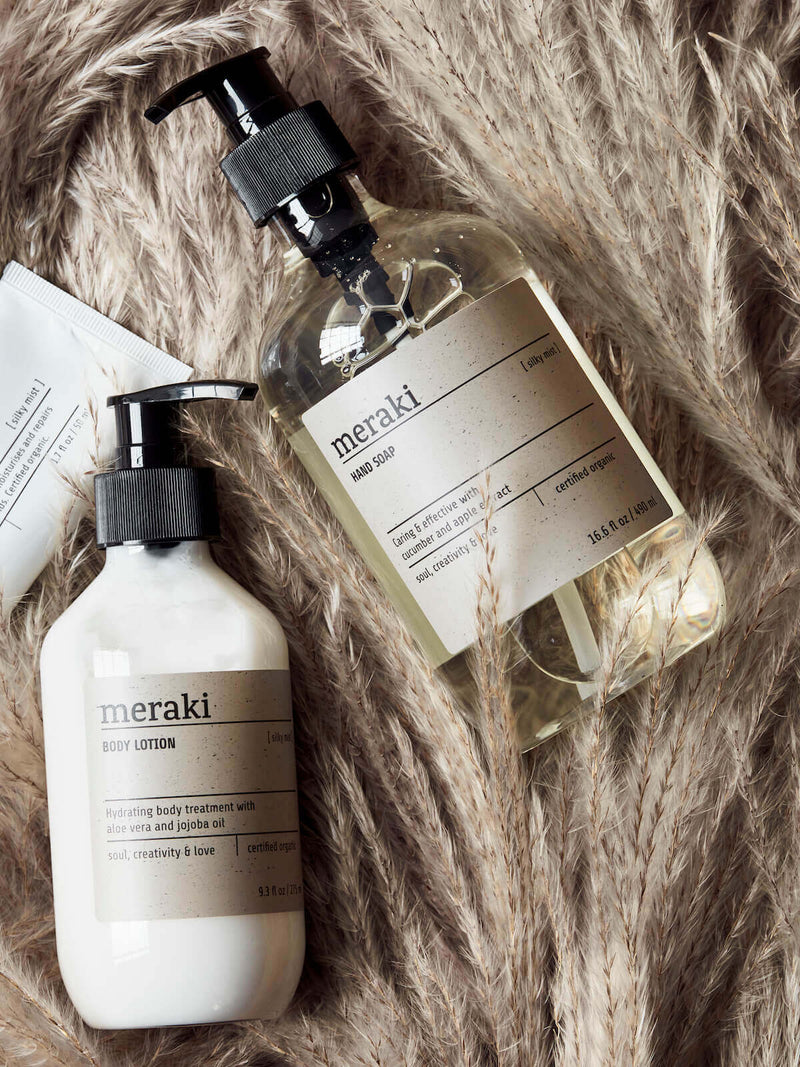 A set of Meraki hand lotion and hand soap handwash on top of natural grass pamper.