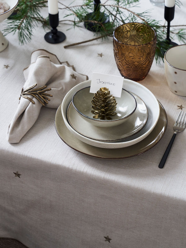 Christmas table with napkin rings, candlesticks, matching tablecloth with embroidered stars in beige. 