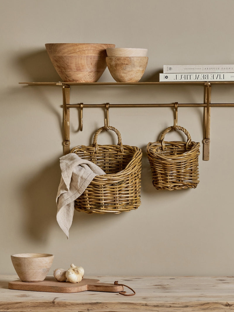 A THATCH Living wall hung wicker baskets and bowls on a wall shelf against a beige wall.
