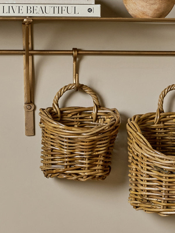 Rattan baskets by THATCH Living and bowls on a wall shelf against a beige wall.