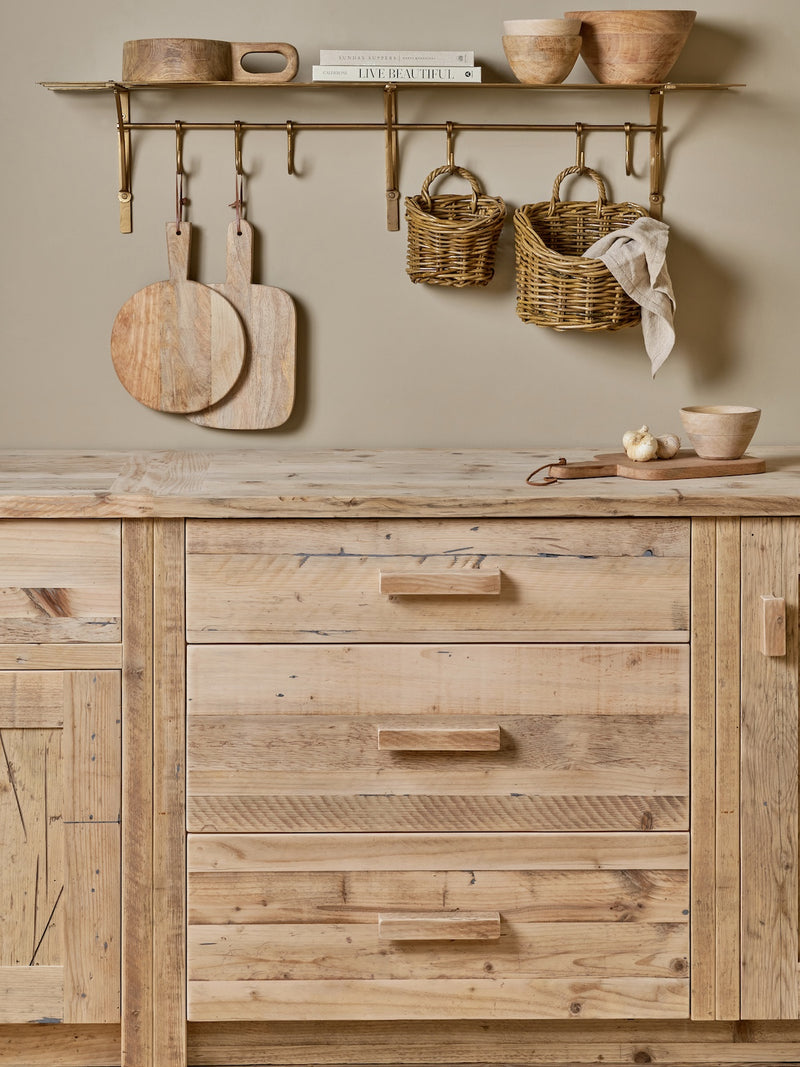 Wooden kitchen cabinets with rustic decor elements on a neutral wall. Rattan baskets by THATCH Living.
