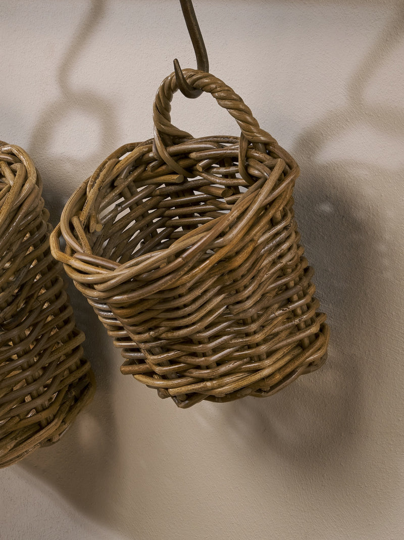 Woven rattan baskets by THATCH Living hanging against a neutral background