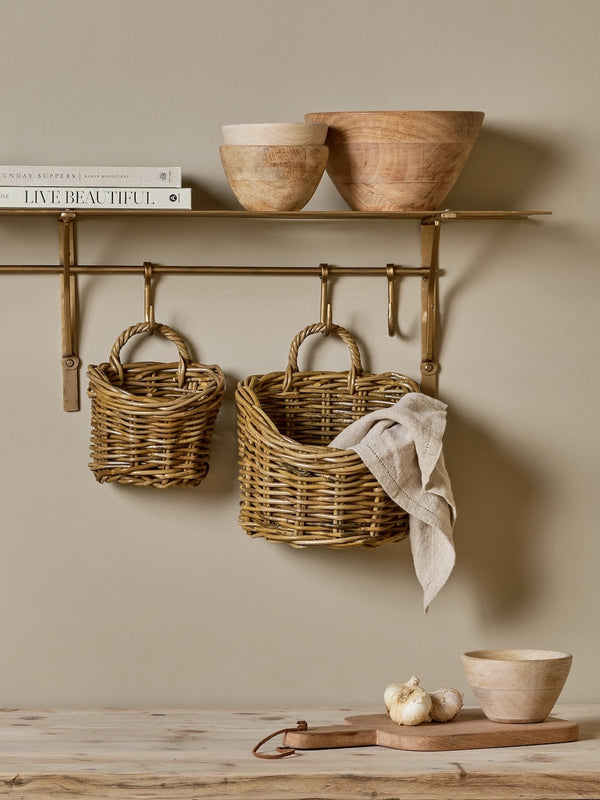 Rattan wall hung baskets by THATCH Living and bowls on a wooden shelf against a beige wall.
