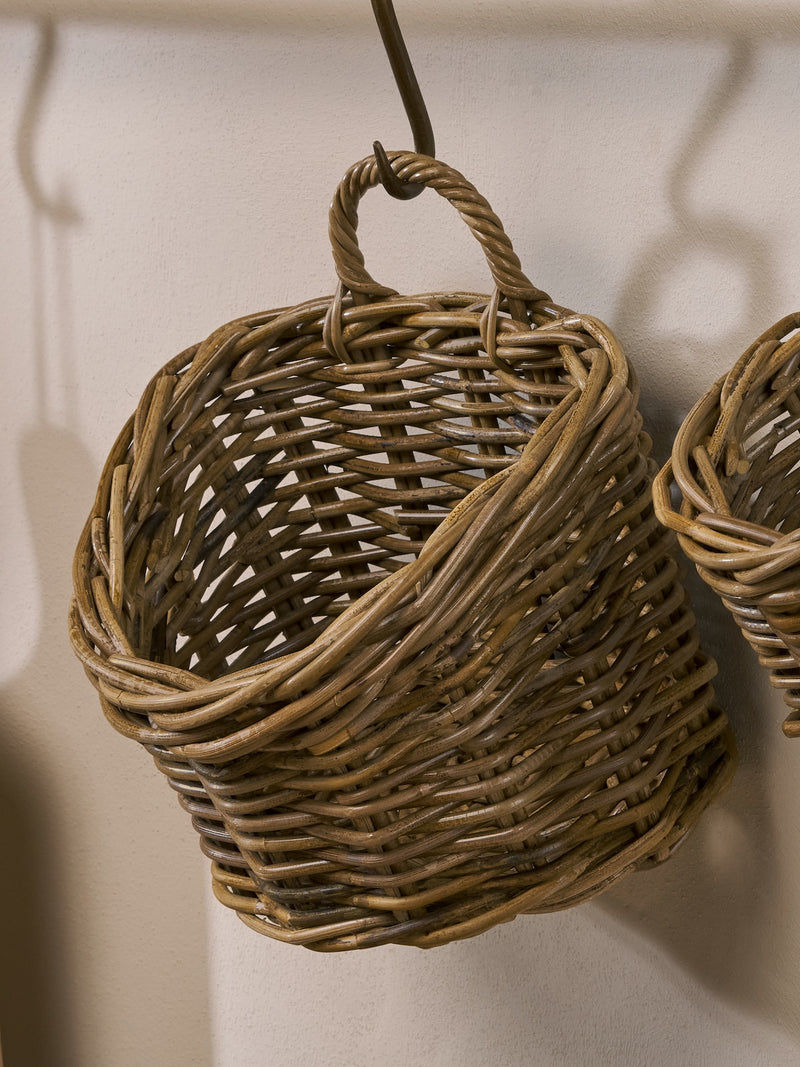 A THATCH Living woven rattan basket hanging against a neutral background 